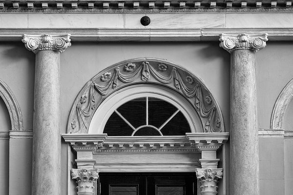 Black and white architectural detail photograph of decorative designs over the doors to the historic Charleston City Hall. Designed by local architect Gabriel Manigault in the Adamesque style, the structure was opened in 1804 to be a branch of the federal bank, but was transferred to the city in 1811 after revocation of the bank's charter by the U.S. Congress.