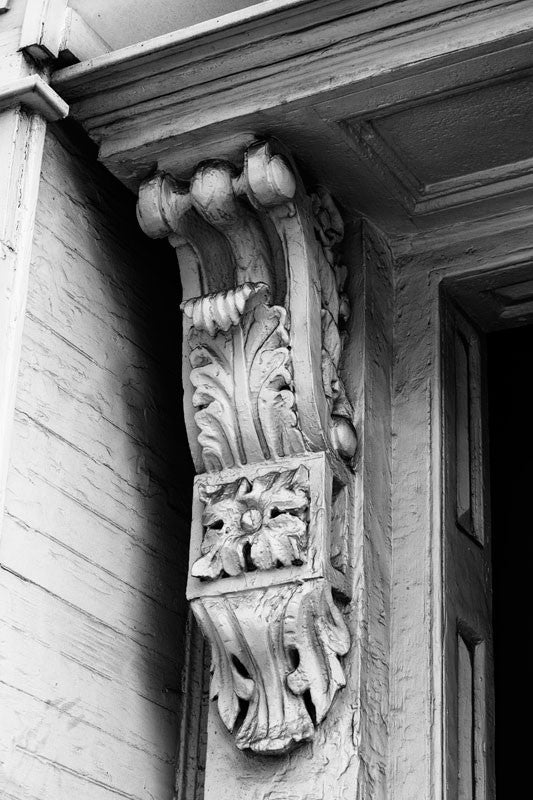 Black and white photograph of an architectural detail -- heavily painted and somewhat dusty ornate woodwork on an old house in Charleston, South Carolina.