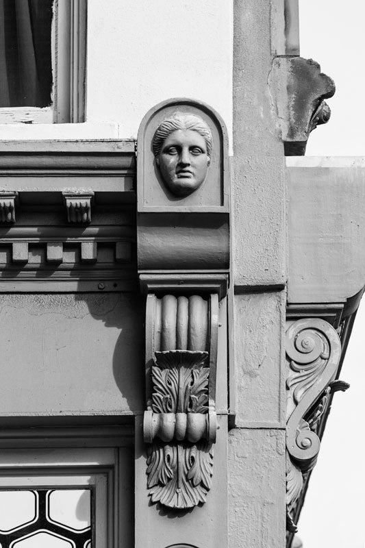 Black and white architectural detail photograph of a female face in the ornamental scrollwork on an 1890s-era building on Charleston's Meeting Street.