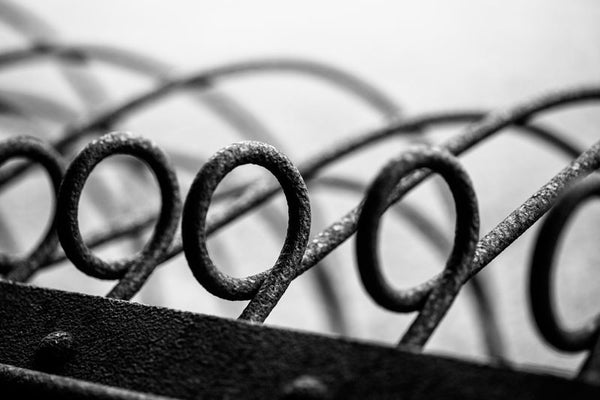 Black and white abstract photograph of rusty metal loops on an antique piece of farm equipment.