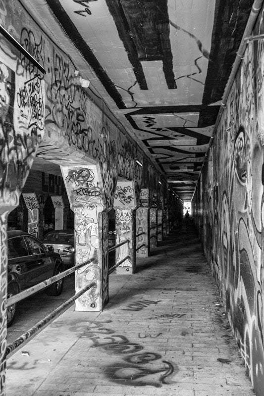 Black and white photograph of the notorious Krog Street Tunnel in the Cabbagetown neighborhood of Atlanta. The tunnel, under a bridge built in 1913, has been covered end-to-end with graffiti and street art.  This photograph is not available for commercial licensing.