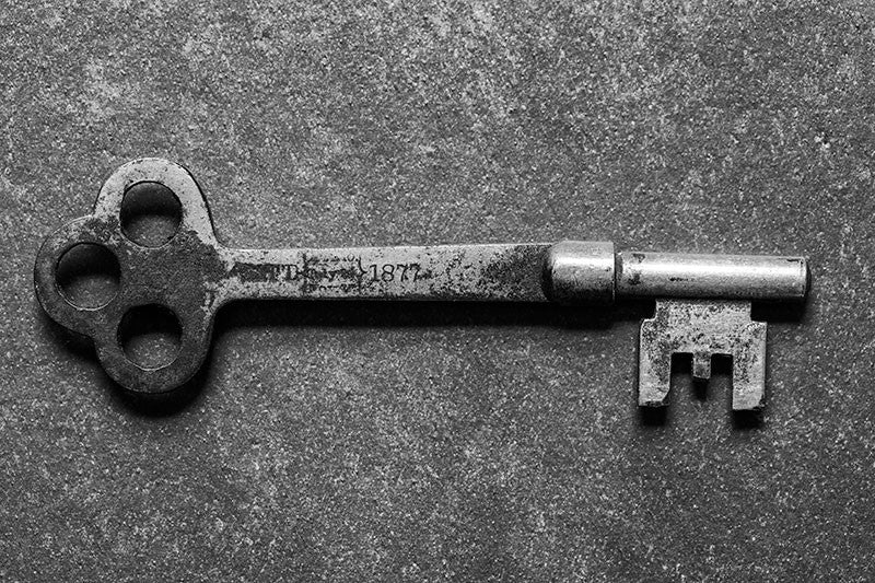 Black and white photograph of an antique door key stamped with the date 1877, found in Charleston, South Carolina.