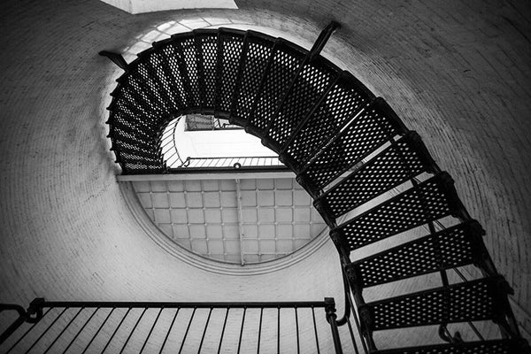 Black and white photograph of the metal stairs spiraling upwards inside the St. Augustine Lighthouse in St. Augustine, Florida. The current lighthouse stands at the north end of Anastasia Island and was built in 1874.