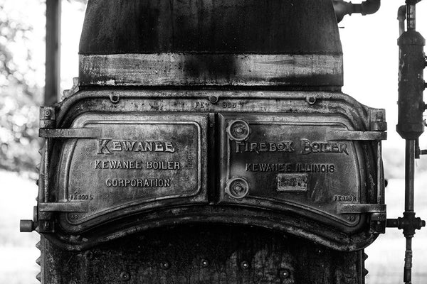 Black and white photograph of the grimy iron doors of an antique Kewanee Firebox Boiler