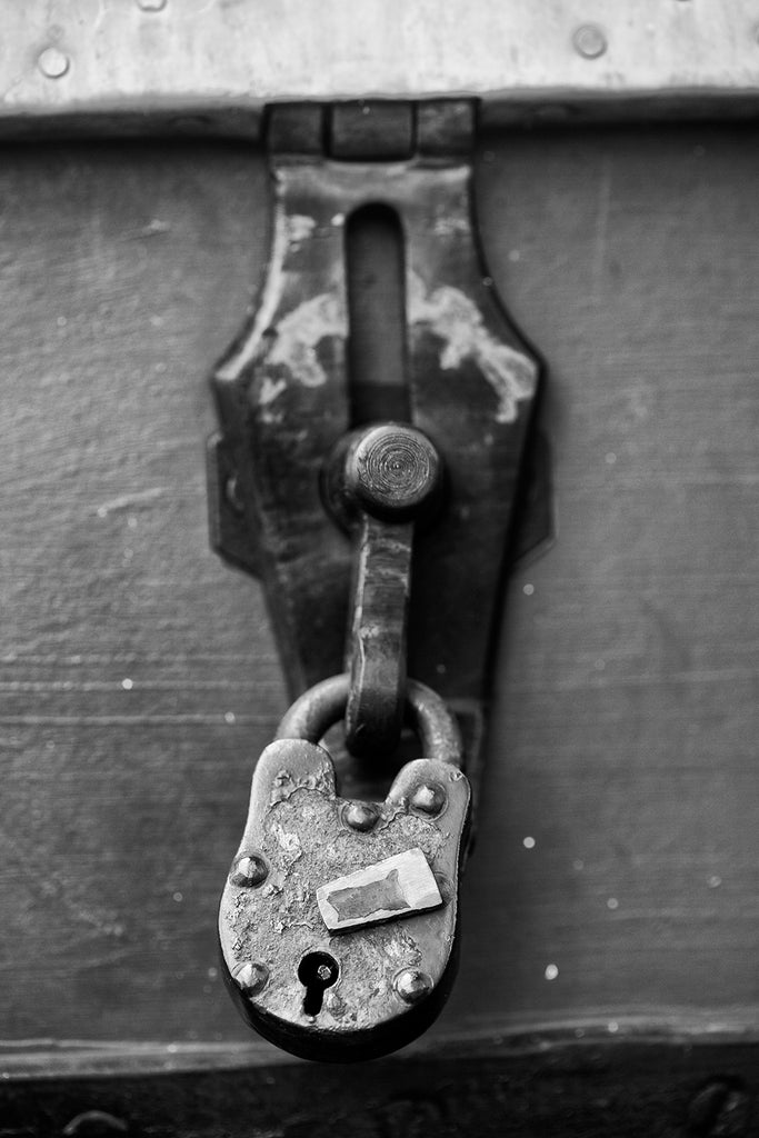 Black and white landscape photograph of an antique padlock secured on an old trunk