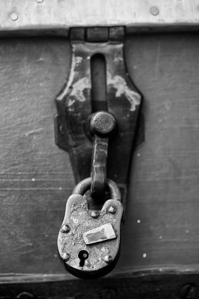 Black and white landscape photograph of an antique padlock secured on an old trunk