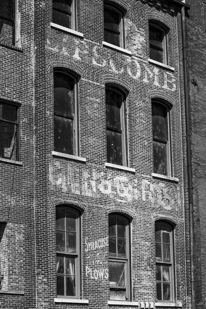 Black and white photograph of fading painted signs and ads on Nashville's old waterfront. At bottom left can be seen the turn-of-the-century Syracuse Plows ad.
