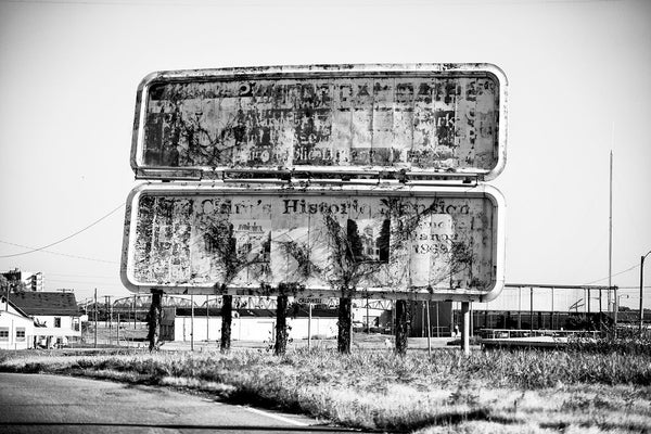 Black and white photograph of fading and peeling billboard signs that once welcomed visitors to the city of Cairo, Illinois, which itself is faded and peeling.