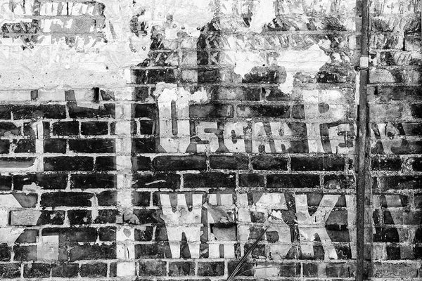 Black and white photograph of an old painted wall ad for Oscar Pepper Whiskey on the side of an old building in the city of Cairo, Illinois. Oscar Pepper established his whiskey brand in 1838, with roots as far back as 1800. The brand went on to become Woodford Reserve, still in production in Kentucky.