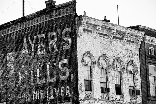 Black and white photograph of a peeling painted wall sign for "Ayer's Pills for the Liver," probably dating to about 1900, on an old riverfront building in Cairo, Illinois.