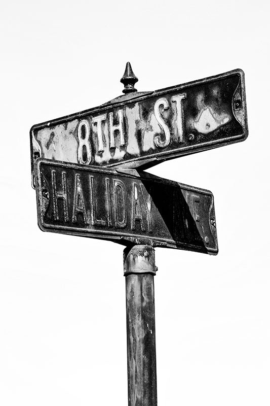 Black and white close-up photograph of a rusty street sign on Haliday Ave at 8th Street in the city of Cairo, Illinois.