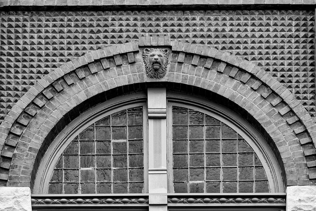 Black and white photograph of a lion's head architectural detail and arched window masonry on a historic building in north Knoxville, Tennessee. 