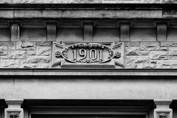 Black and white photograph detail of a decorative date placard that says 1901, on a historic Union Street building in Nashville, Tennessee. Builders of this era always dated their structures, as though they expected them to last into posterity. And, many of them have.