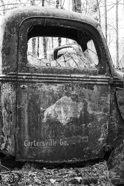 Black and white fine art photograph of a rusty, abandoned antique truck with a faded rhinoceros painted on it's heavily weathered door.