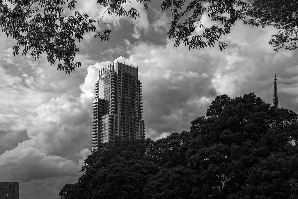 Black and white cloudscape photograph of Charlotte, North Carolina featuring The Vue, the fifth tallest building in Charlotte.