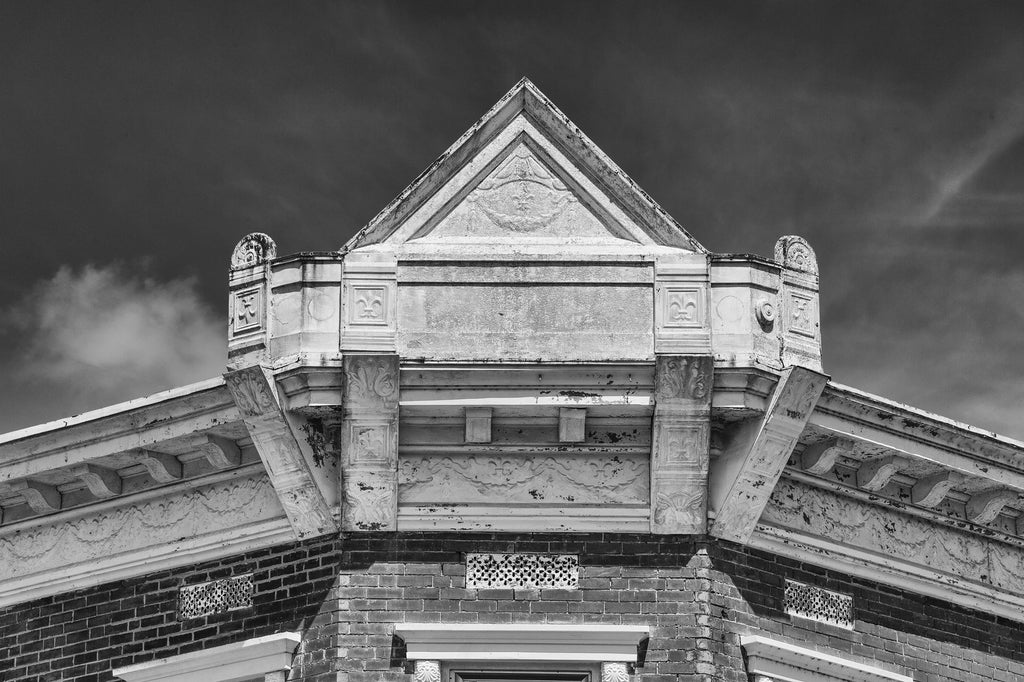 Black and white architectural detail photograph of a decorative antique pressed-tin roofline façade with fleur-de-lis in picturesque Ste. Genevieve, Missouri.