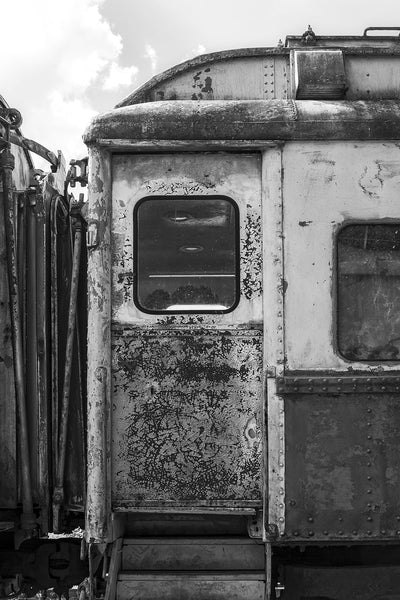 Black and white detail photograph of the exterior door to an antique railroad dining car, featuring an intense cracking pattern in the old paint.