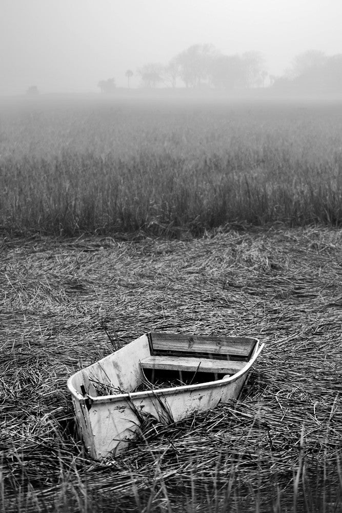 Black and white photograph of an abandoned boat on the reeds of a Charleston marsh at low tide.
