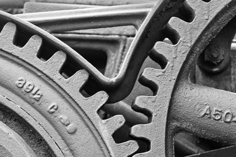 Black and white photograph of large gear wheels with big teeth in an antique machine.