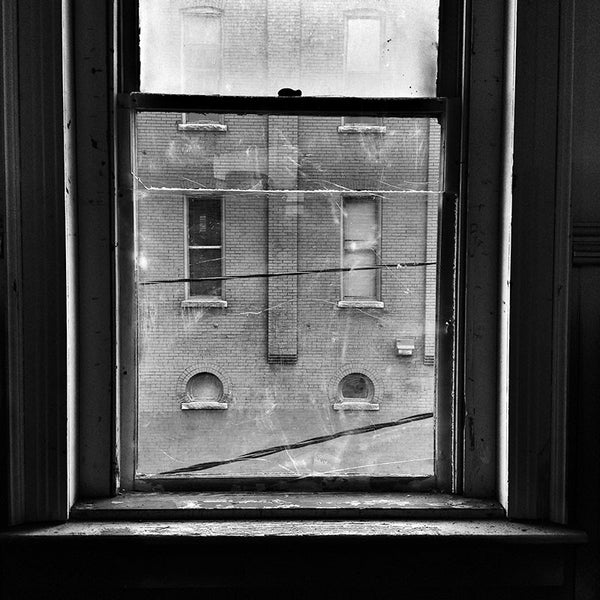 Black and white photograph looking through an old window from the second story of a historic building on Charlotte Avenue in Nashville. This view of another old building across the street, must be similar to what one would have seen from the same window 100 years ago.