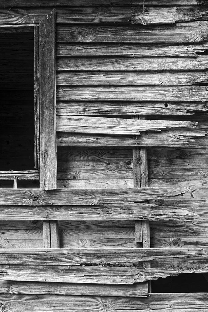 Black and white detail photograph of beautifully textured and weathered wood on the exterior of an abandoned old house.