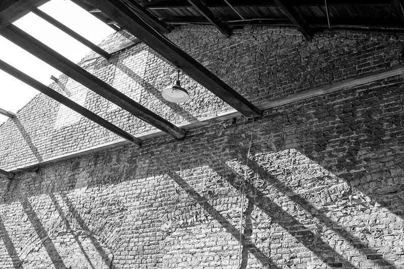 Black and white industrial photograph of an old brick warehouse with a missing roof.
