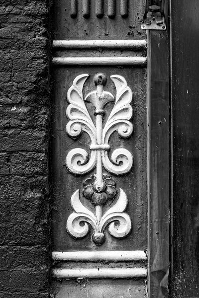 Black and white photograph of an ornate cast iron architectural detail seen on the main street of a small town. 