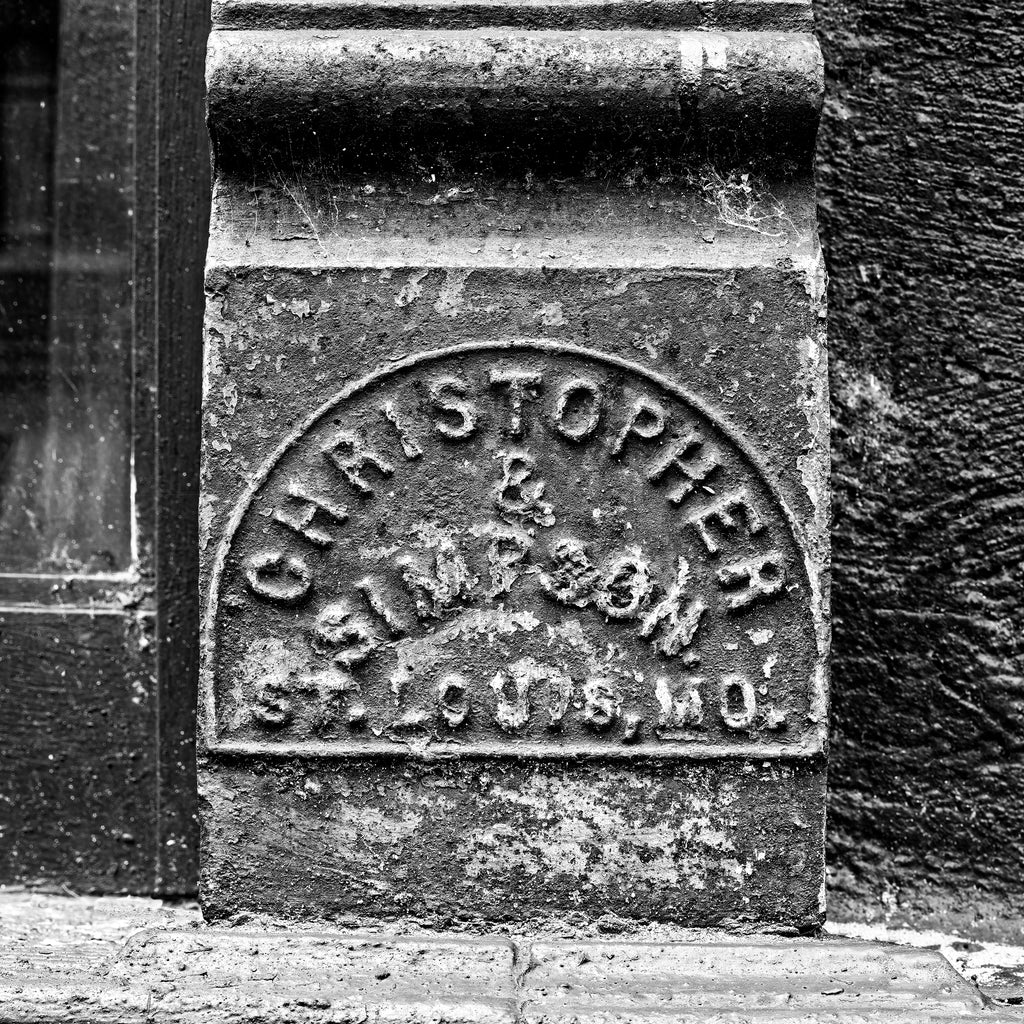 Black and white photograph of an antique name plate for Christopher & Simpson, a St. Louis-based company that manufactured cast iron storefronts that can still be seen on the main streets of many small towns across America. (Square format)