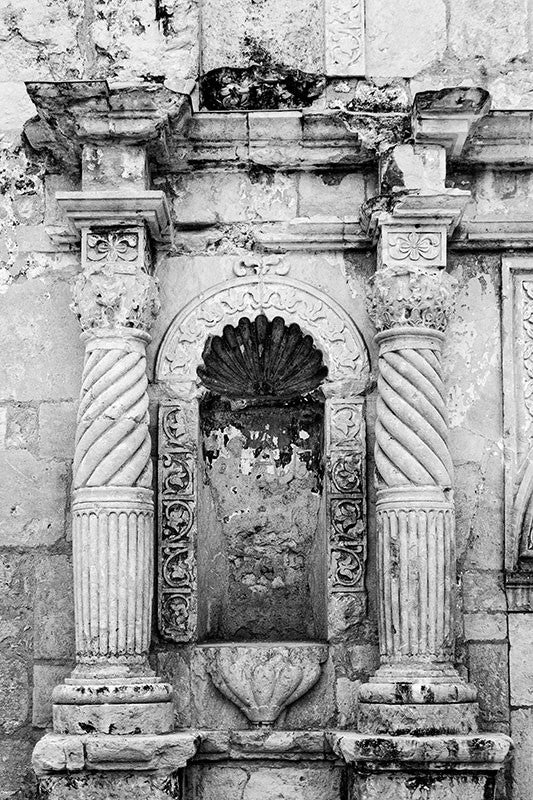 Black and white architectural detail photograph of the carved stone columns on the front of the world-famous Alamo.