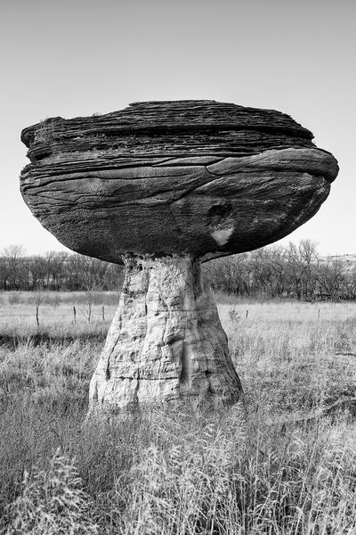 Black and white fine art photograph of a mushroom-shaped rock formation in the landscape of the American prairie.