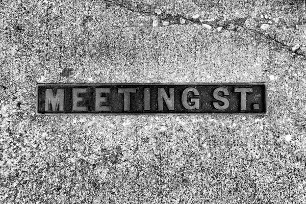 Black and white photograph of a Meeting Street sidewalk sign in historic Charleston, South Carolina. 