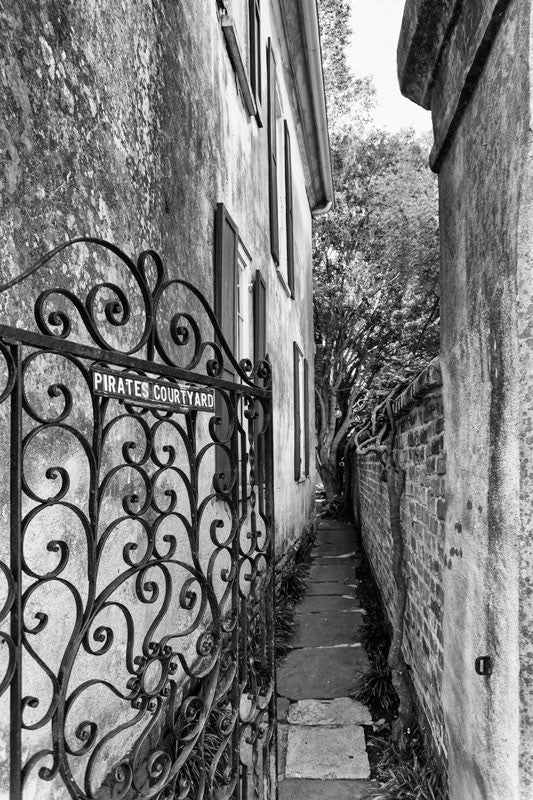 Black and white photograph of an alley to the Pirate's Courtyard in the French Quarter section of Charleston, South Carolina. 