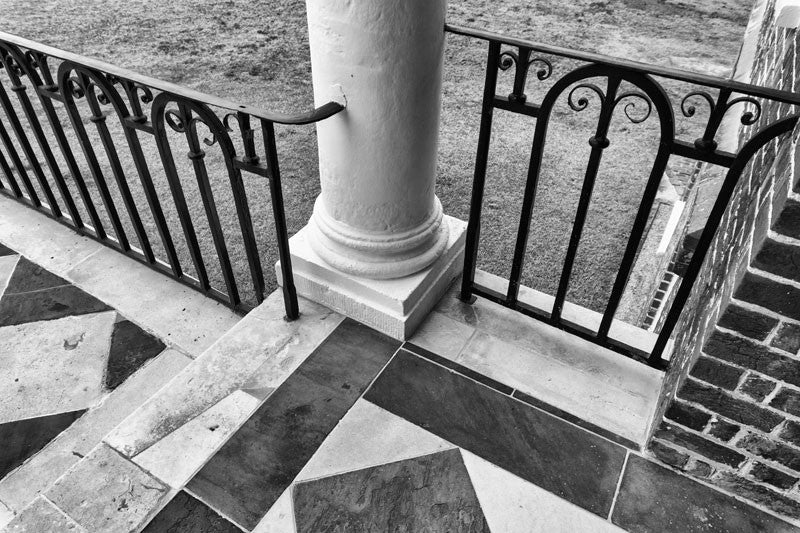 Black and white photograph of the portico at Drayton Hall, a 1740s English-style Palladian plantation home nine miles from Charleston on the Ashley River. Drayton Hall is the only old plantation home to survive both the revolutionary war and thUS Civil War intact. The home is now maintained in a preserved, not restored, condition. 