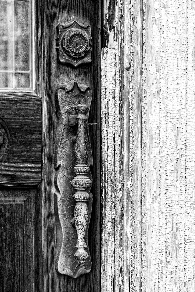 Black and white detail photograph of a fancy door handle on the antique door of an abandoned Main Street in the ghost town of Pamplin City, Virginia. The street is lined with 11 historic, vacant buildings.