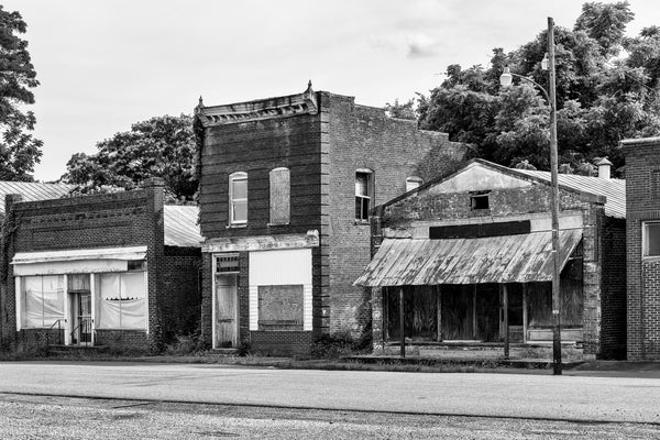 Black and white photograph of a row of abandoned storefronts along the deserted old Main Street in Pamplin City, Virginia.