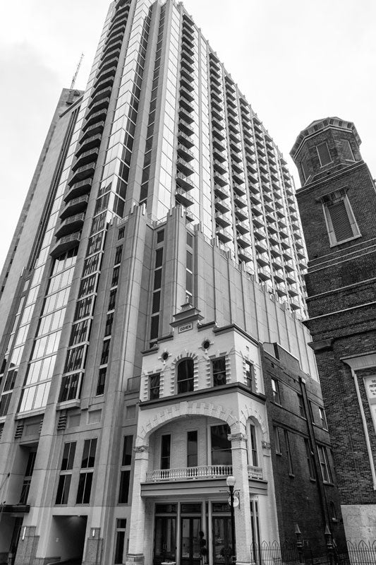 Black and white photograph of the historic Cohen Building on Church Street in Nashville, tucked in beside a towering modern condo development. The structure was built in 1890 with the Cohens residing on the second and third floors, and operating a jewelry store at street level. 