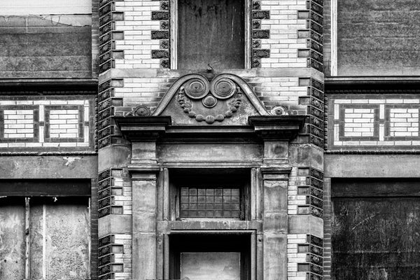 Black and white photograph of the tarnished architectural details and scrollwork motif on the front of an old building on Nashville's 3rd Avenue. Historically this part of Nashville was home to many furniture stores.