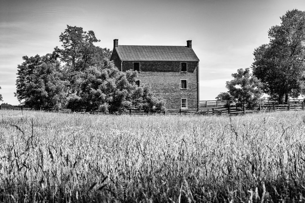 Black and white photograph of historic brick architecture set among the bucolic landscape of Appomattox, Virginia.