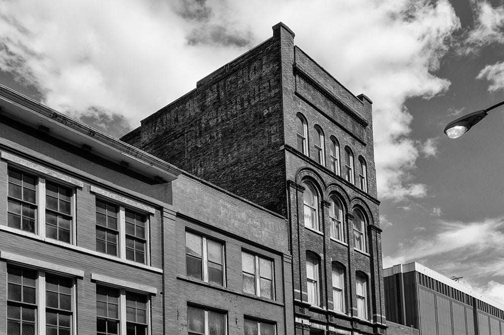 Black and white architectural photograph of a five-story brick building at 208 N. Third in Nashville, Tennessee. Constructed in 1900, this red brick gem features a beautifully fading painted ad for the Bradford Nichol Furniture company, which was open for business by at least 1870 at 25 and 27 North College Street in Nashville, according to a listing in The Masonic Record, published that year. 