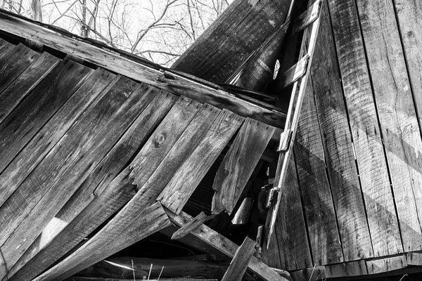 Black and white photograph of angled beams and wooden planks from an old collapsed hay barn.