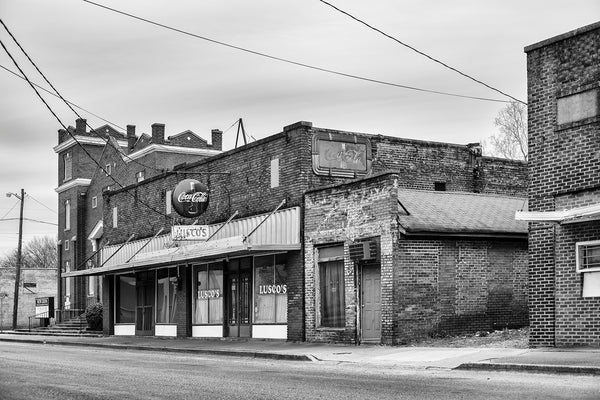Black and white photograph of a block of historic brick buildings with several fading vintage signs in the Mississippi Delta at Greenwood.