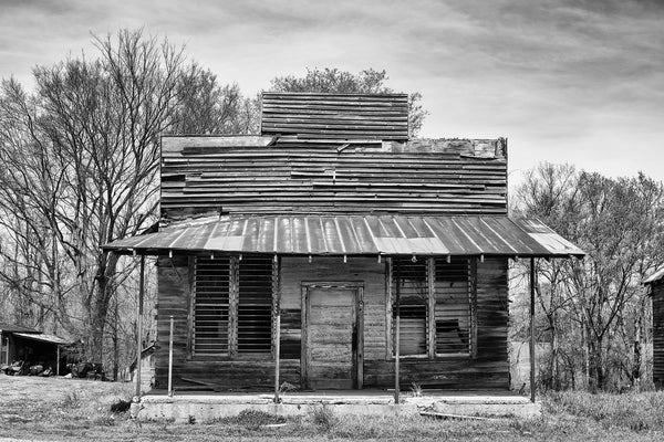 Black and white architectural photograph of an old, abandoned commercial building, most likely a storefront.