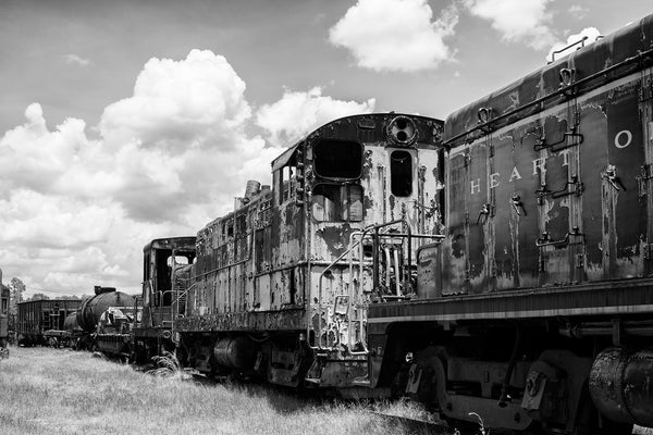 Black and white photograph of old rusty railroad cars sitting on tracks.