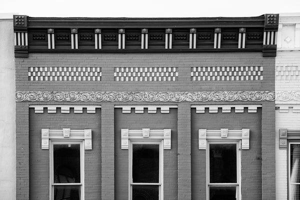 Black and white architectural photograph of beautifully ornate details on the second story of a historic small town storefront.