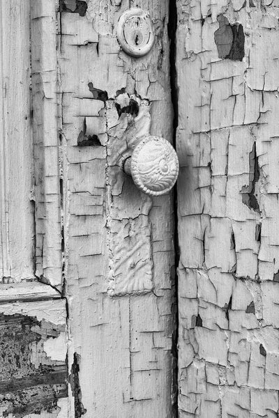 Black and white photograph of a beautifully textured old door on an abandoned building covered in cracked and peeling paint.