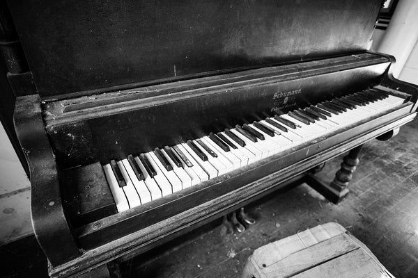 Black and white photograph of an old black piano found inside an abandoned church in the ghost town at Rodney, Mississippi.