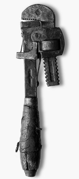 Large-format black and white photograph of an antique pipe wrench with a cracked handle that was repaired at some point with a fraying leather wrap.