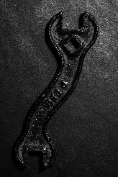 Dramatic black and white photograph of an antique International Harvester S-shaped tractor wrench. On the reverse is scratched the name of the tool's former owner "Jared S."