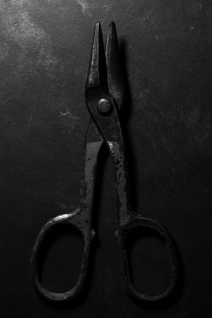 Dramatic black and white photograph of a pair of antique Samson 83 metal shears with red paint on the handles shot in low light