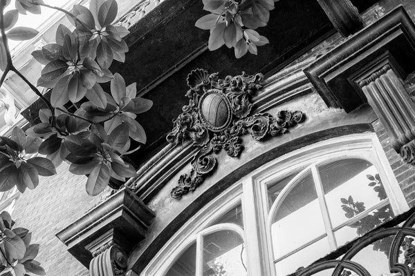Black and white architectural detail photograph of an ornate decorative crest over the window of Savannah's historic and notorious Mercer-Williams House. Built in 1868, the house is famous as the location of the killing in Midnight in the Garden of Good and Evil.
